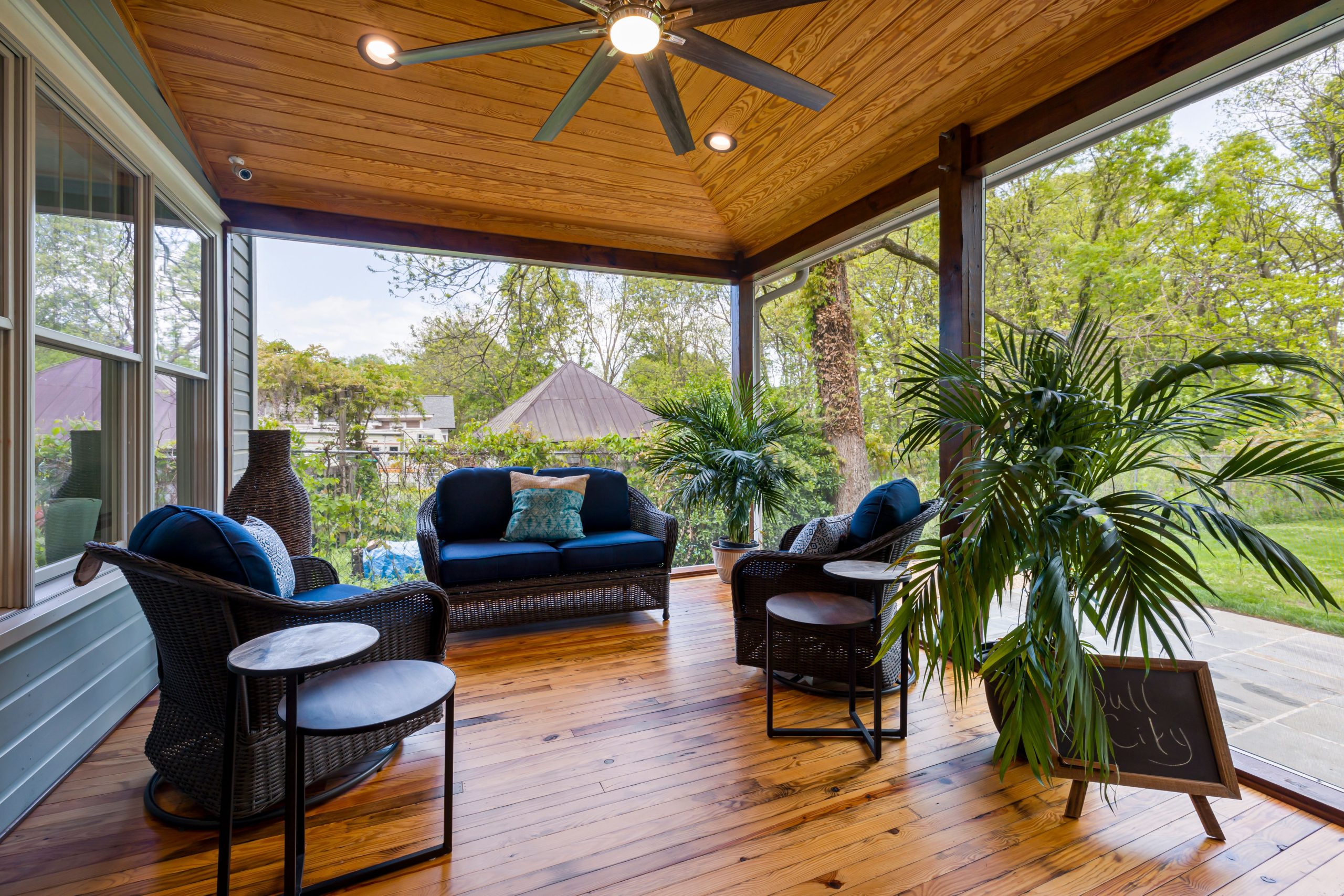 Stylish outdoor patio with cushioned seating on wooden flooring and lush greenery